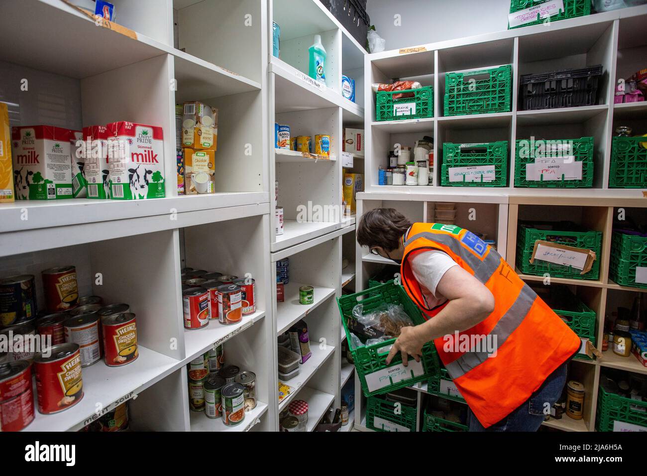Volunteer worker Vicky  in local food bank packing shelves and holding donations , Lewisham Donation Hub, London , England  . Stock Photo