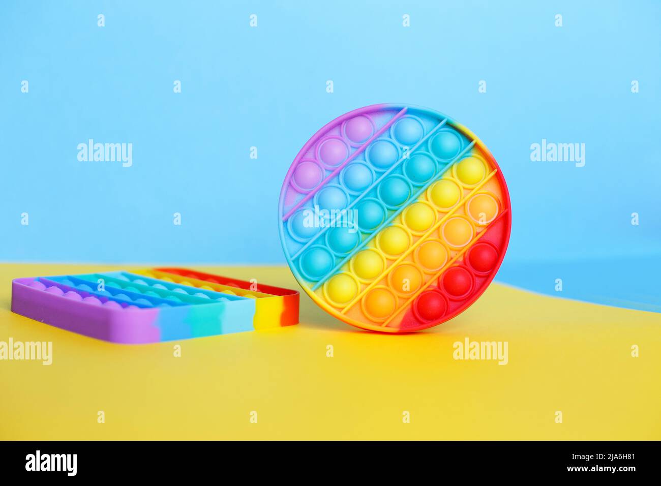 a modern trendy silicone toy pop on a multicolored background. children's educational antistress toy Stock Photo