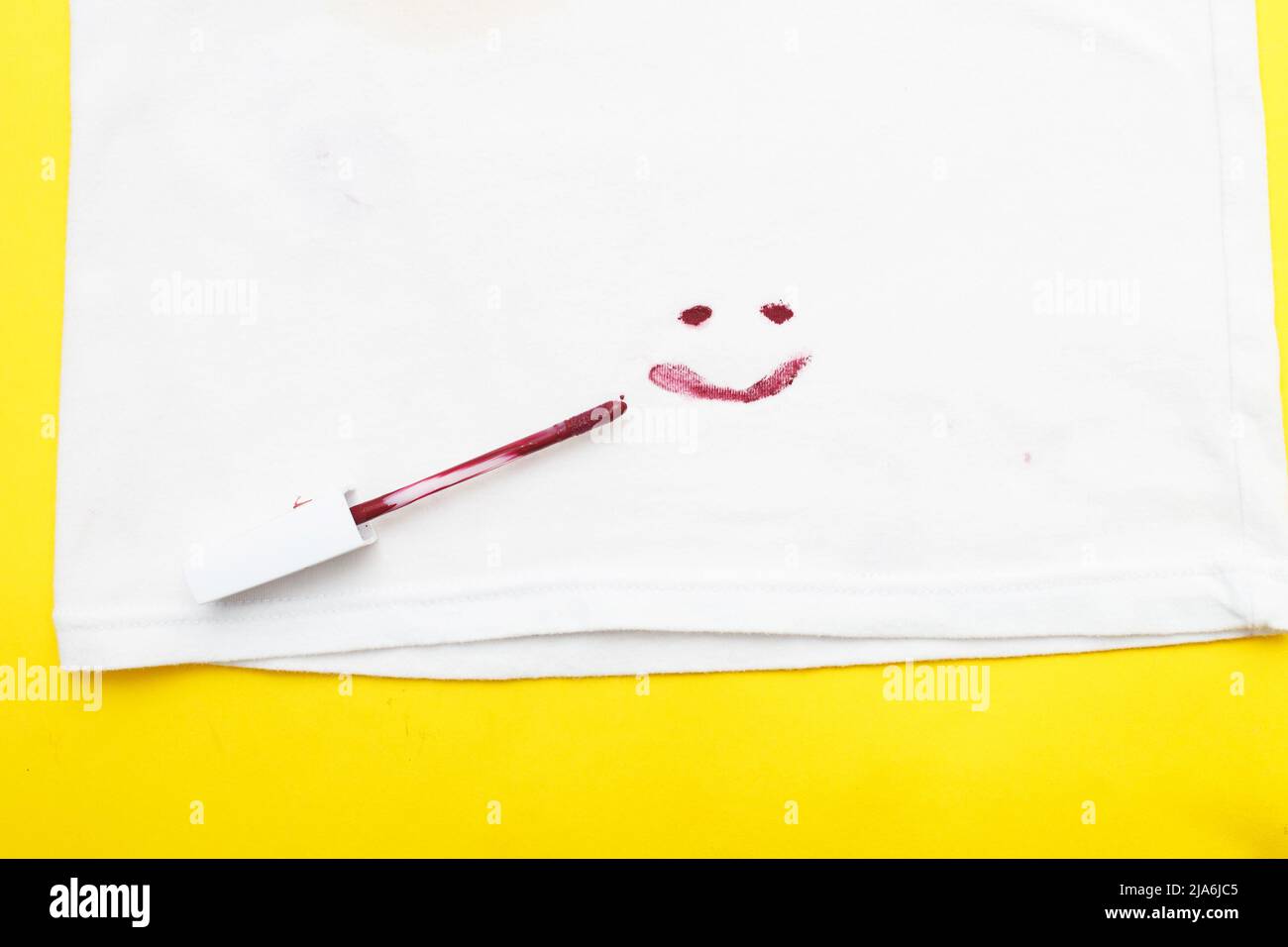 red lipstick on a white clothes with dirty stain in the form of smile. Stock Photo