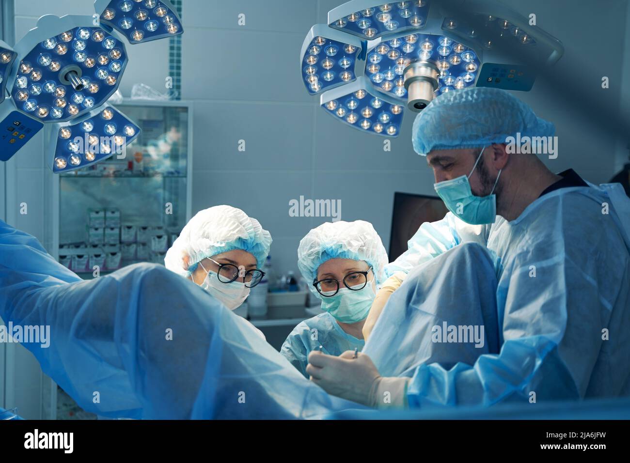 Team of doctors in surgery theater operating on person Stock Photo - Alamy