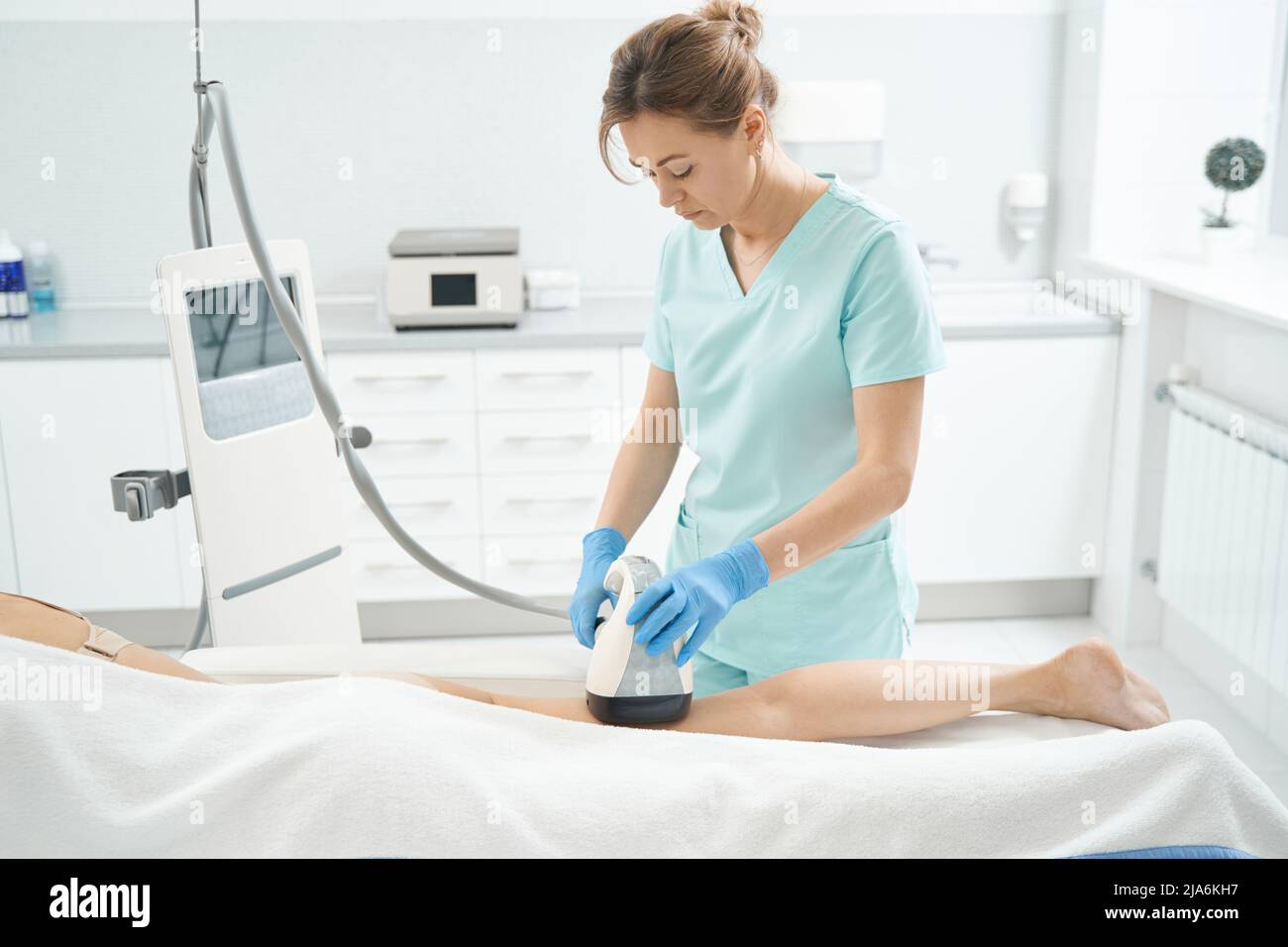 Beautician using vela shape apparatus on female leg Stock Photo - Alamy