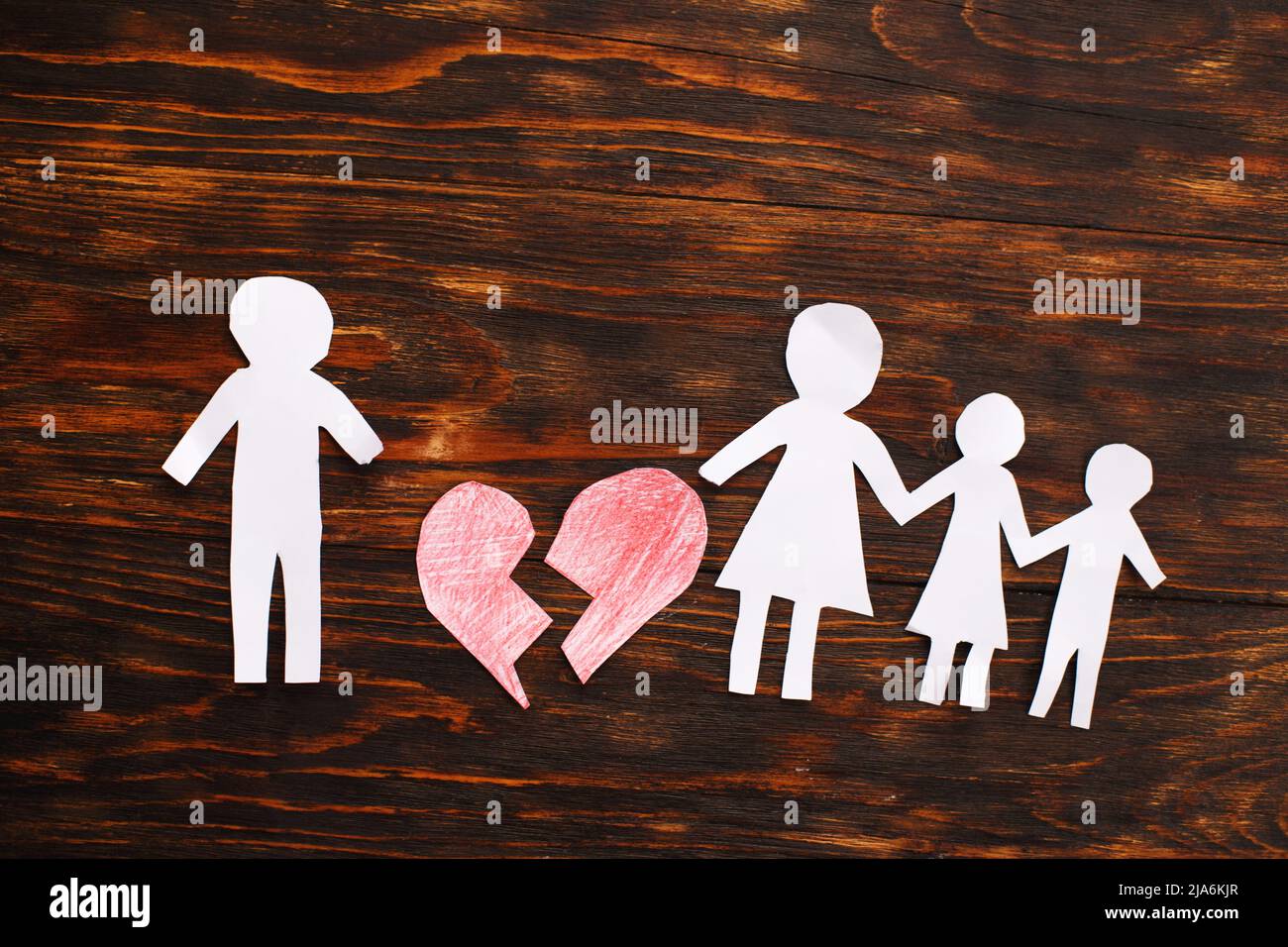 Paper chain cut family with broken heart on wooden background. Divorce and broken family concept. Stock Photo