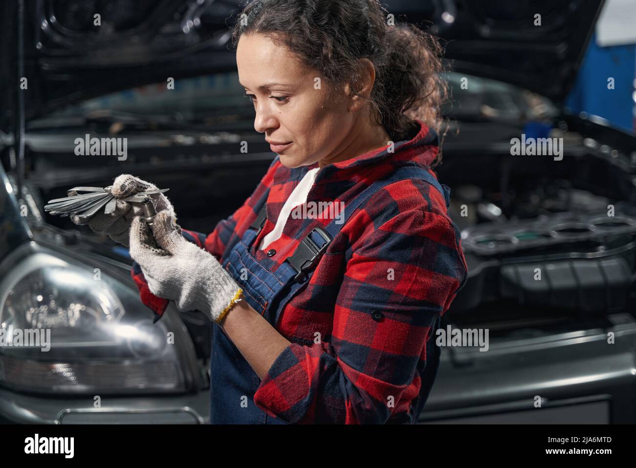 Female auto mechanic repairing car bolt in automobile garage Stock