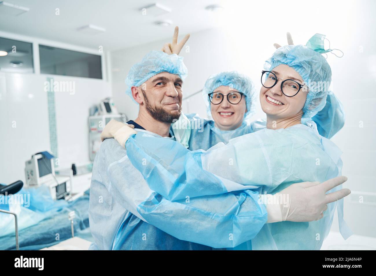 Nurse giving bunny ears to two colleagues in medical room Stock Photo ...