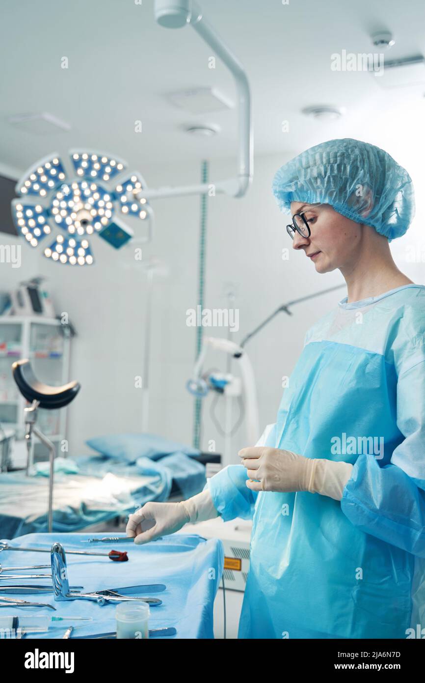 Side view of nurse taking laparoscopic instrument from tray Stock Photo