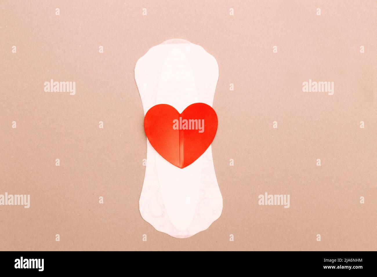 Feminine sanitary pad with a red heart on pink background. Stock Photo