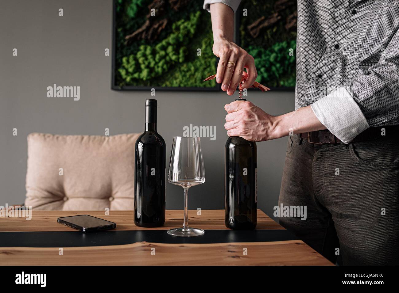 Man opening bottle of wine with corkscrew Stock Photo