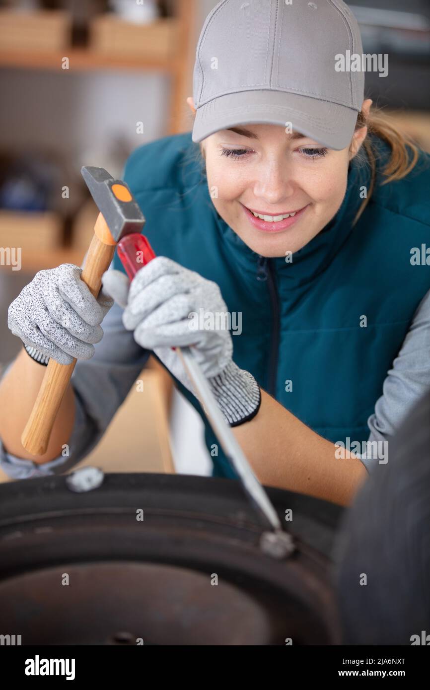 female mechanic using a hammer while working on a tyre Stock Photo