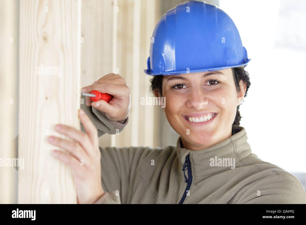 happy woman screws a screw in a wooden construction Stock Photo - Alamy