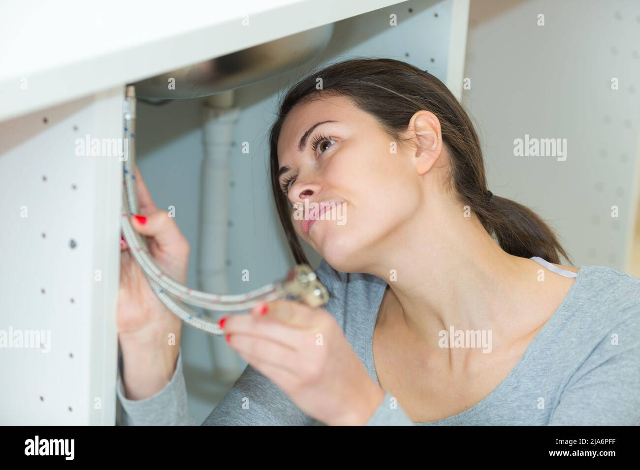 woman inserting connections under the sink Stock Photo Alamy