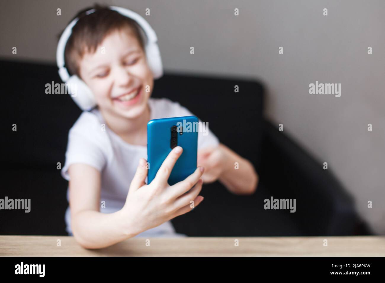 leisure, children, technology and people concept - smiling boy with smartphone and headphones having video call at home. child with mobile Stock Photo