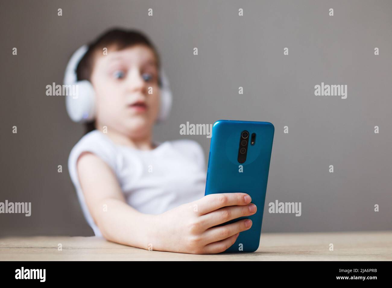 leisure, children, technology and people concept - surprise boy with smartphone and headphones having video call at home. child with mobile Stock Photo