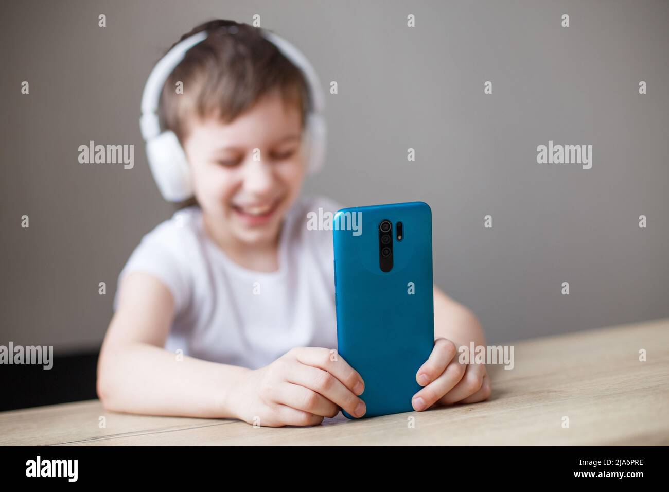 leisure, children, technology and people concept - smiling boy with smartphone and headphones having video call at home. child with mobile Stock Photo