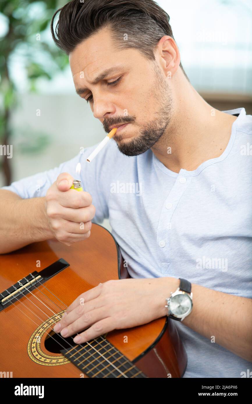 male guitarist lighting a cigarette Stock Photo