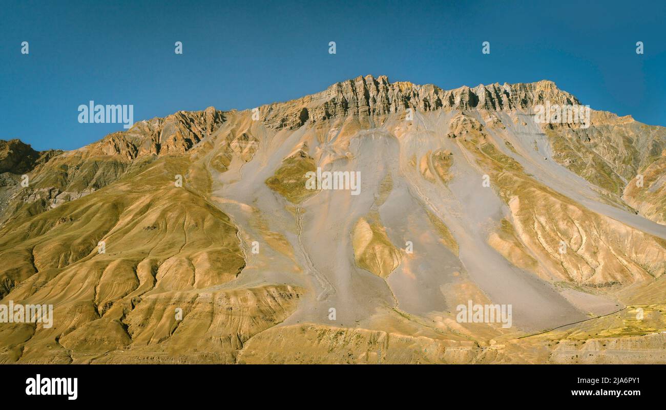 Panoramic view of Himalaya mountains with rocky ridges and scarred slopes under blue sky in summer near Kaza, Himachal Pradesh, India. Stock Photo