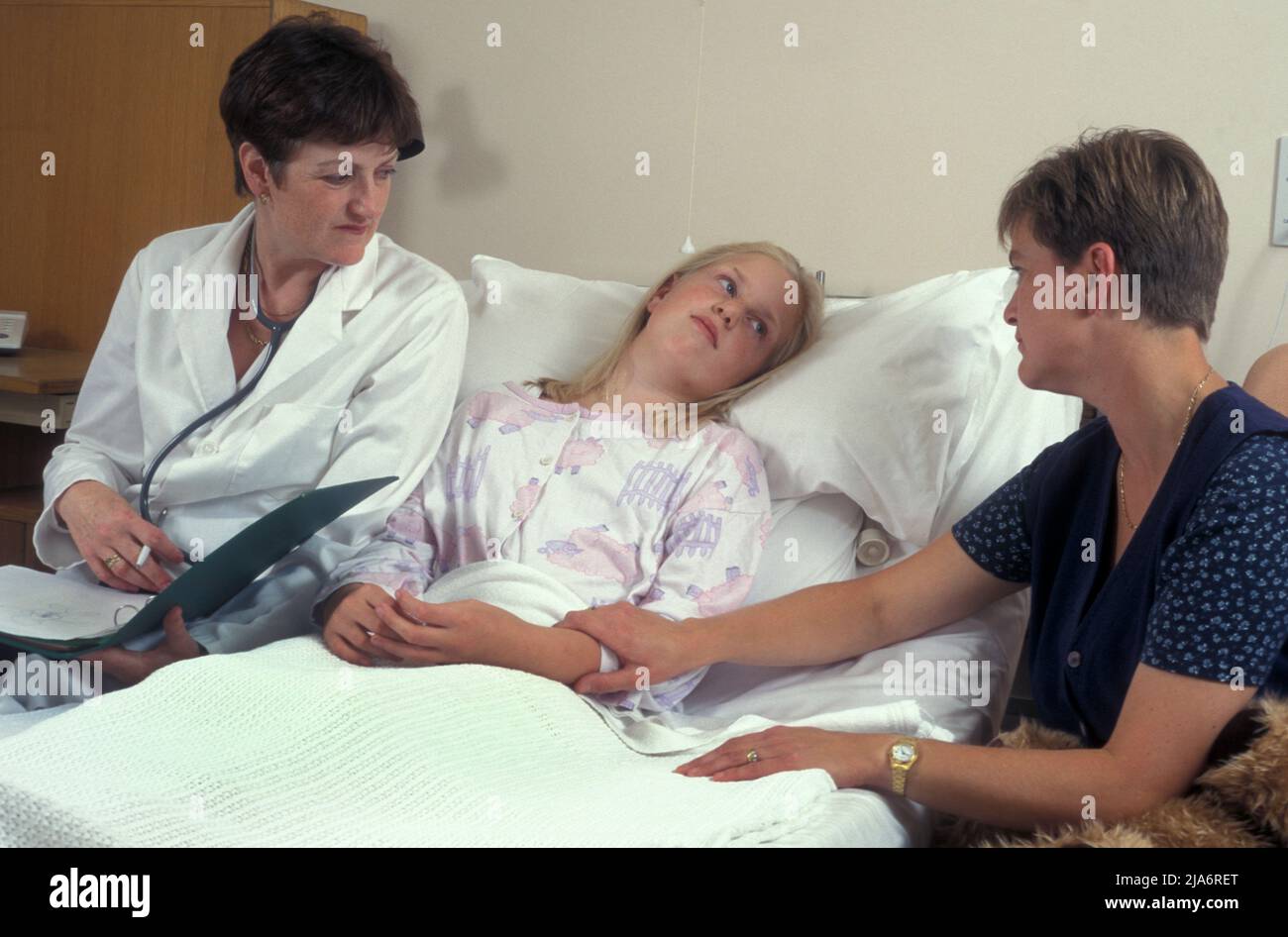 mother and consultant with young girl in hospital bed Stock Photo