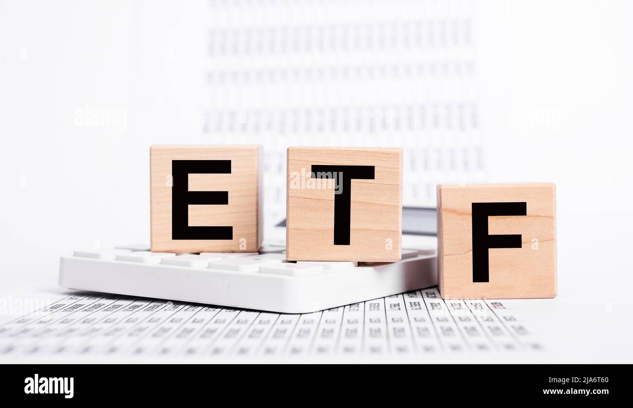 Exchange traded fund. Wooden cubes with ETF text and papers with statistics showing stock market drop. Economic recession and crisis. Investment and trade concept. High quality photo Stock Photo