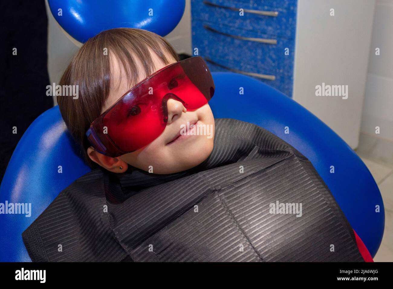 The little kid is in the safety glasses at the dentist. Stock Photo