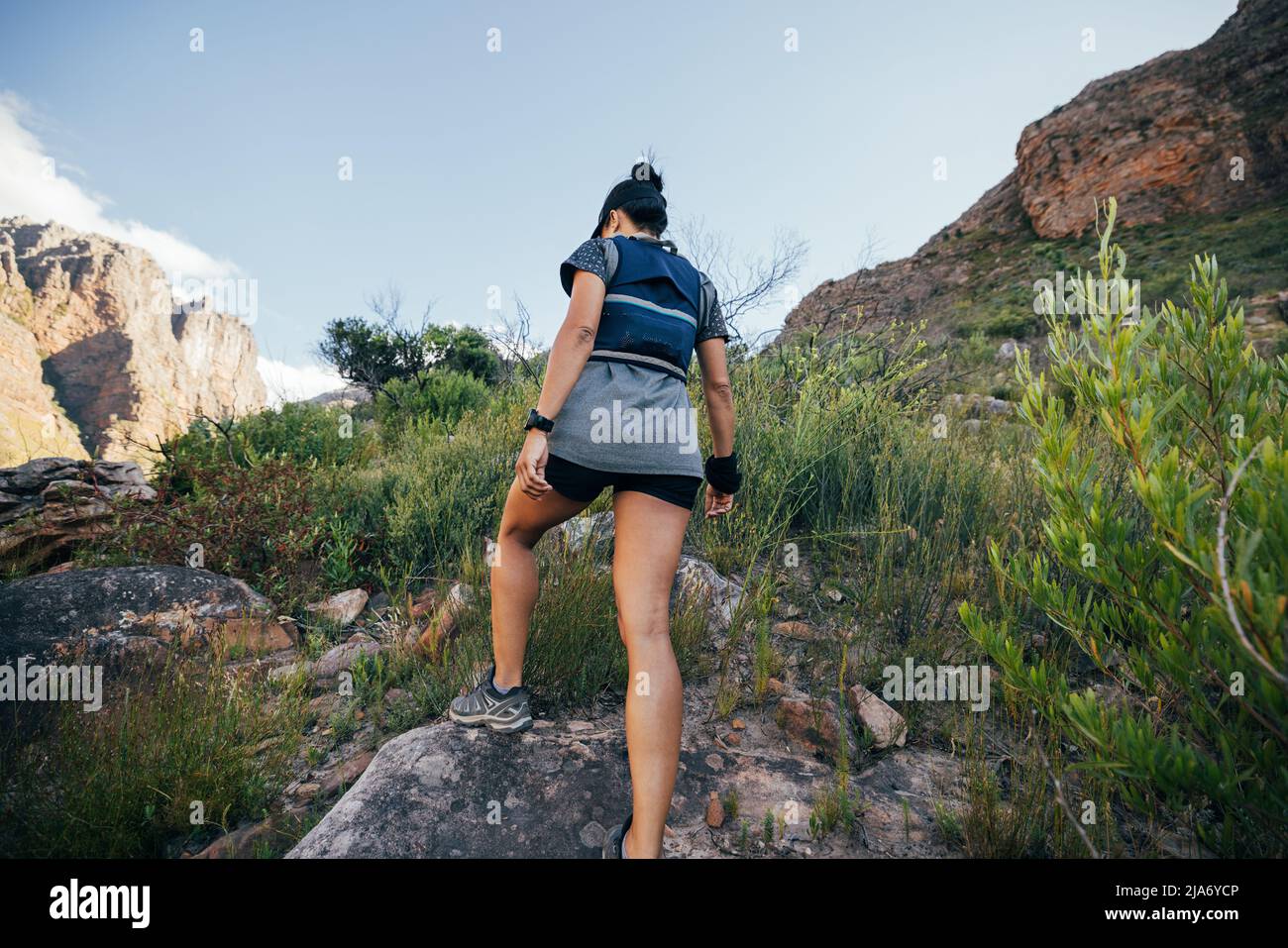 Rear view of woman walking up on mountain trail. Female hiker in ...