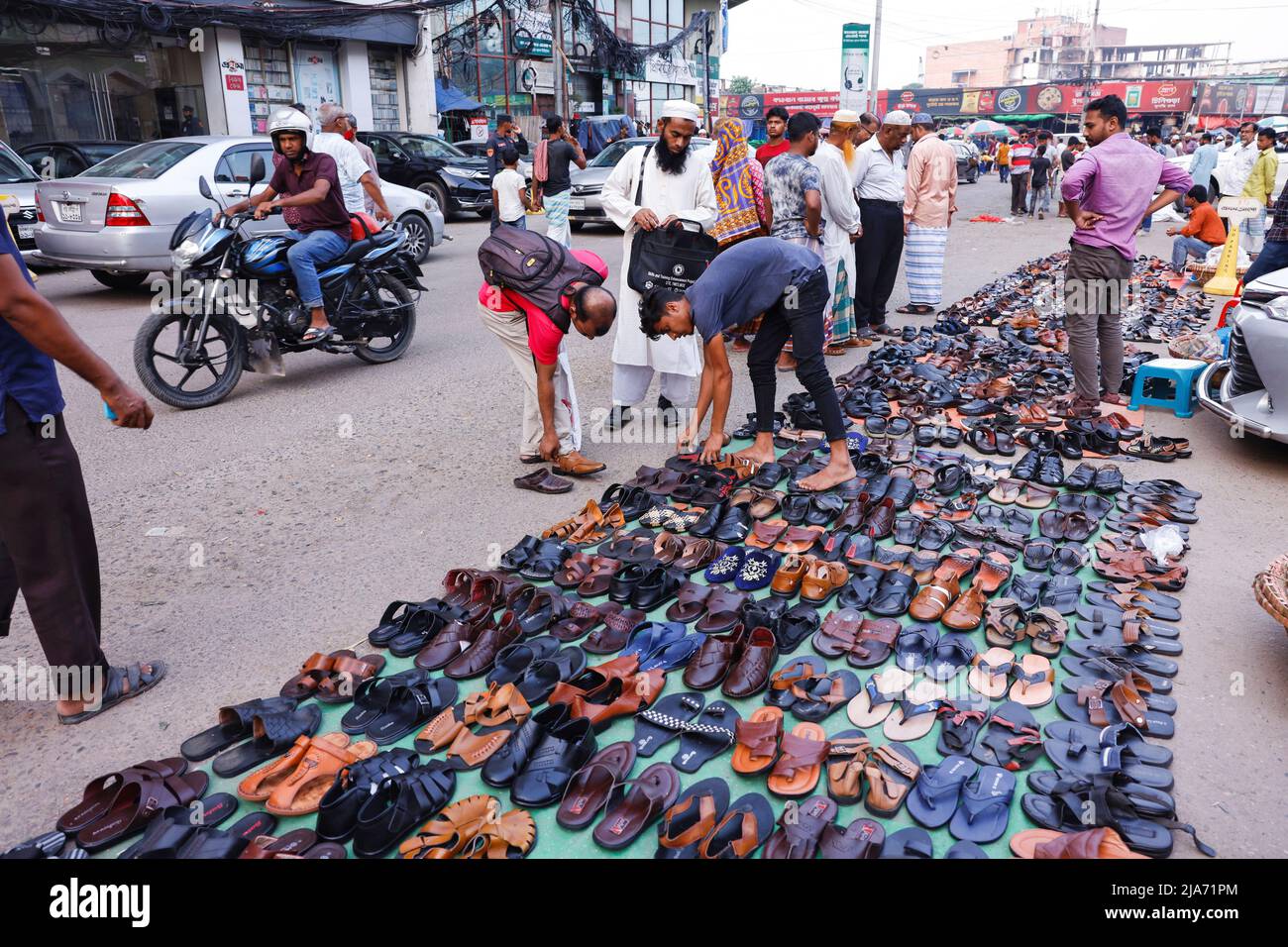 People shop for footwear at a street vendor's stall in Dhaka, Bangladesh, May 28, 2022. REUTERS/Mohammad Ponir Hossain Stock Photo