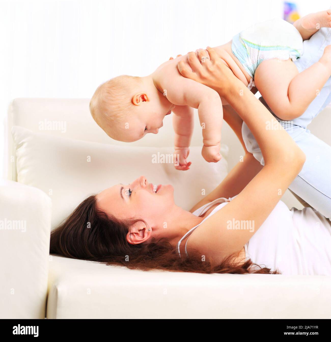 happy beautiful young mother and baby laying on sofa Stock Photo - Alamy