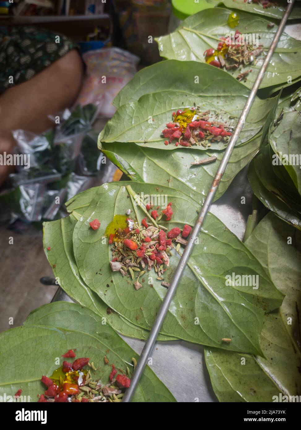 Betel leaves or mitha paan being prepared with ingredients like areka nut or supari and other condiments in a shop for sale in india. A famous practic Stock Photo