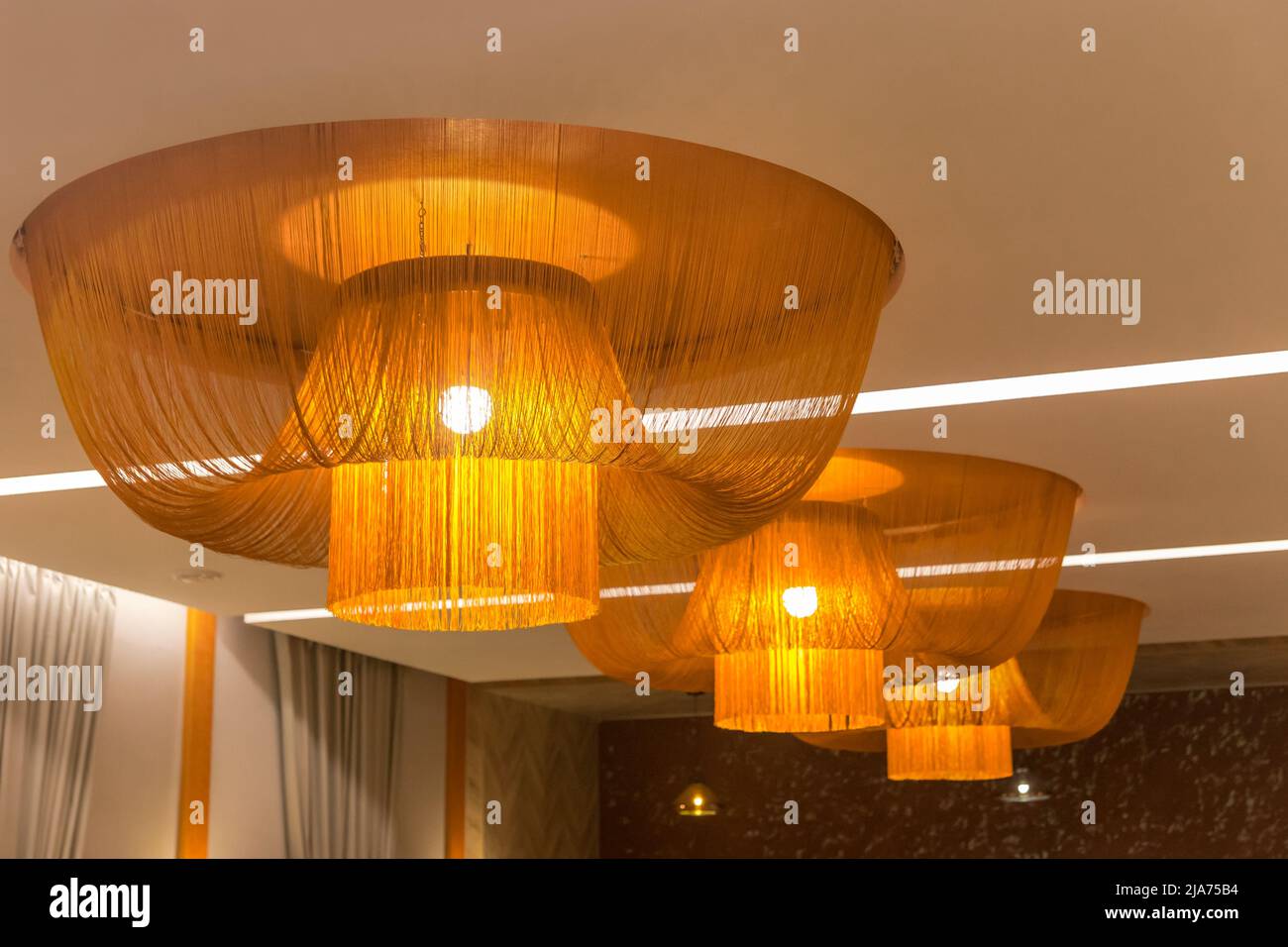 Modern ceiling interior design with vintage orange fabric decorations chandelier light abstract decor room. Stock Photo