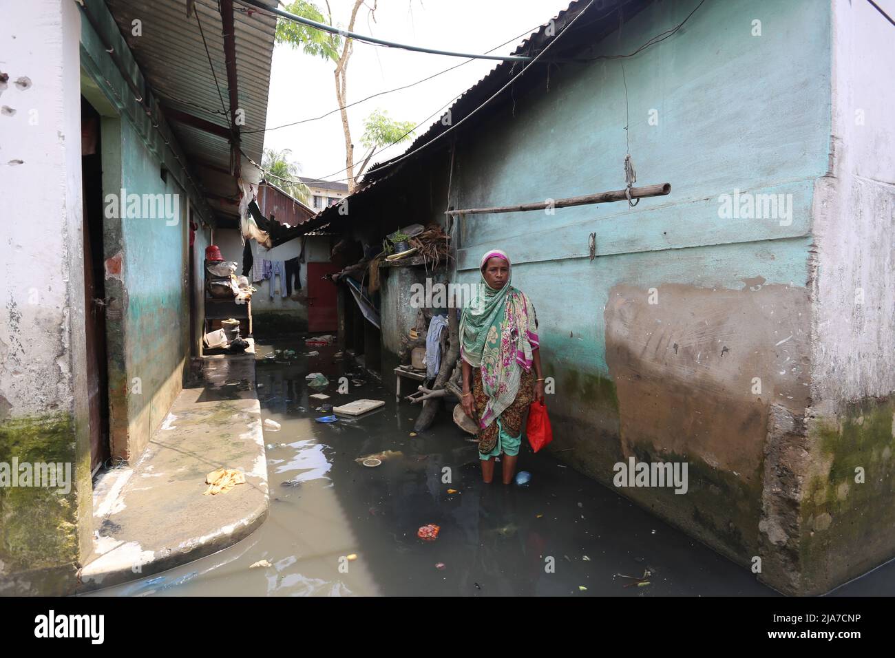 Sylhet, Bangladesh. 24th May, 2022. Woman crossing dirty water in Sylhet,  Bangladesh .The flash flood water enters the houses in the Sylhet city due  to the rise in water level in the