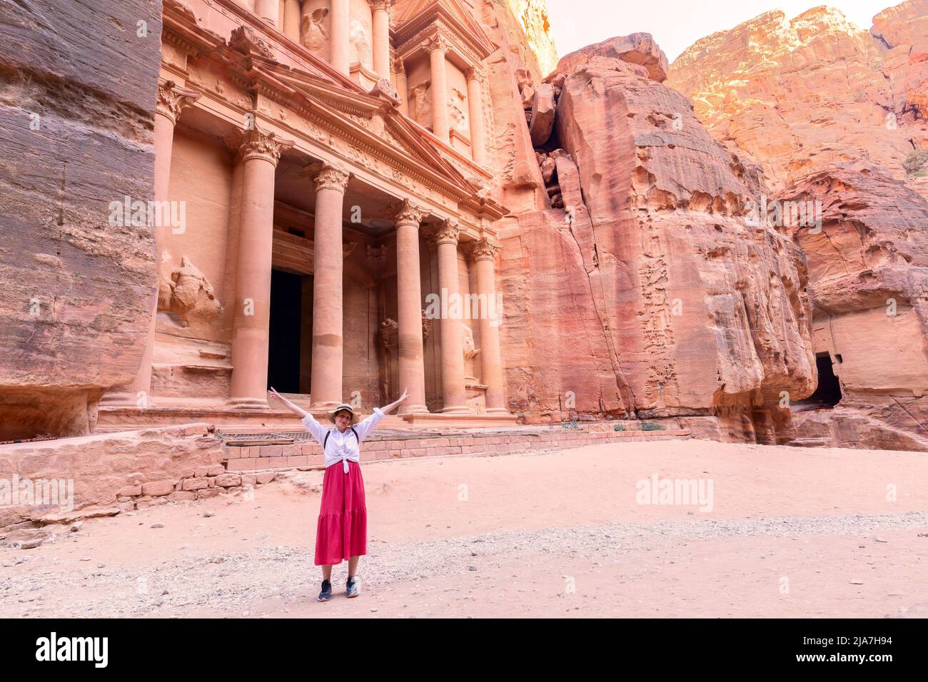 Rear view of beautiful young woman standing with open arms  in front of the treasure of petra, Jordan Stock Photo
