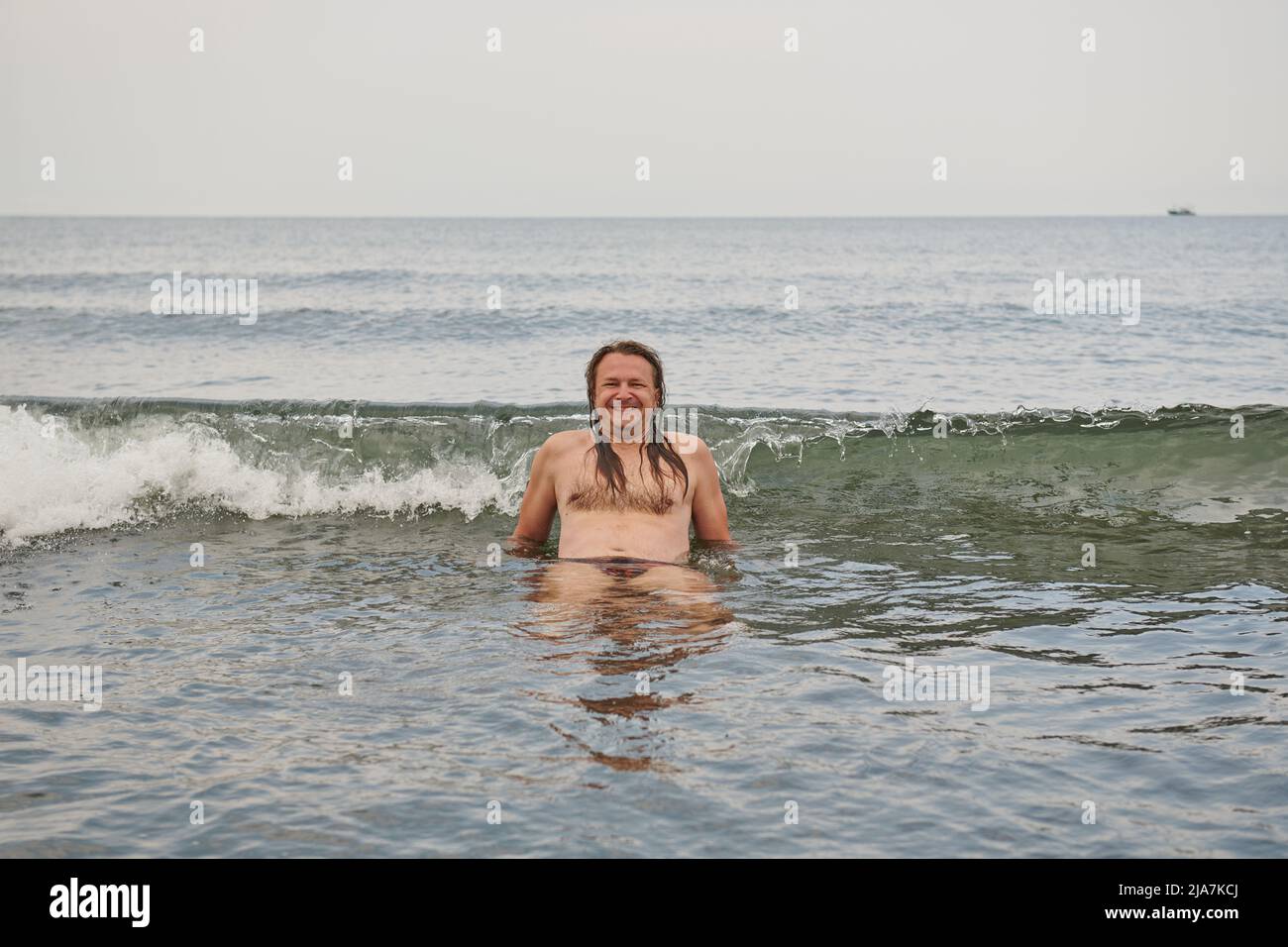 hairy man in the sea on the crest of a wave Stock Photo