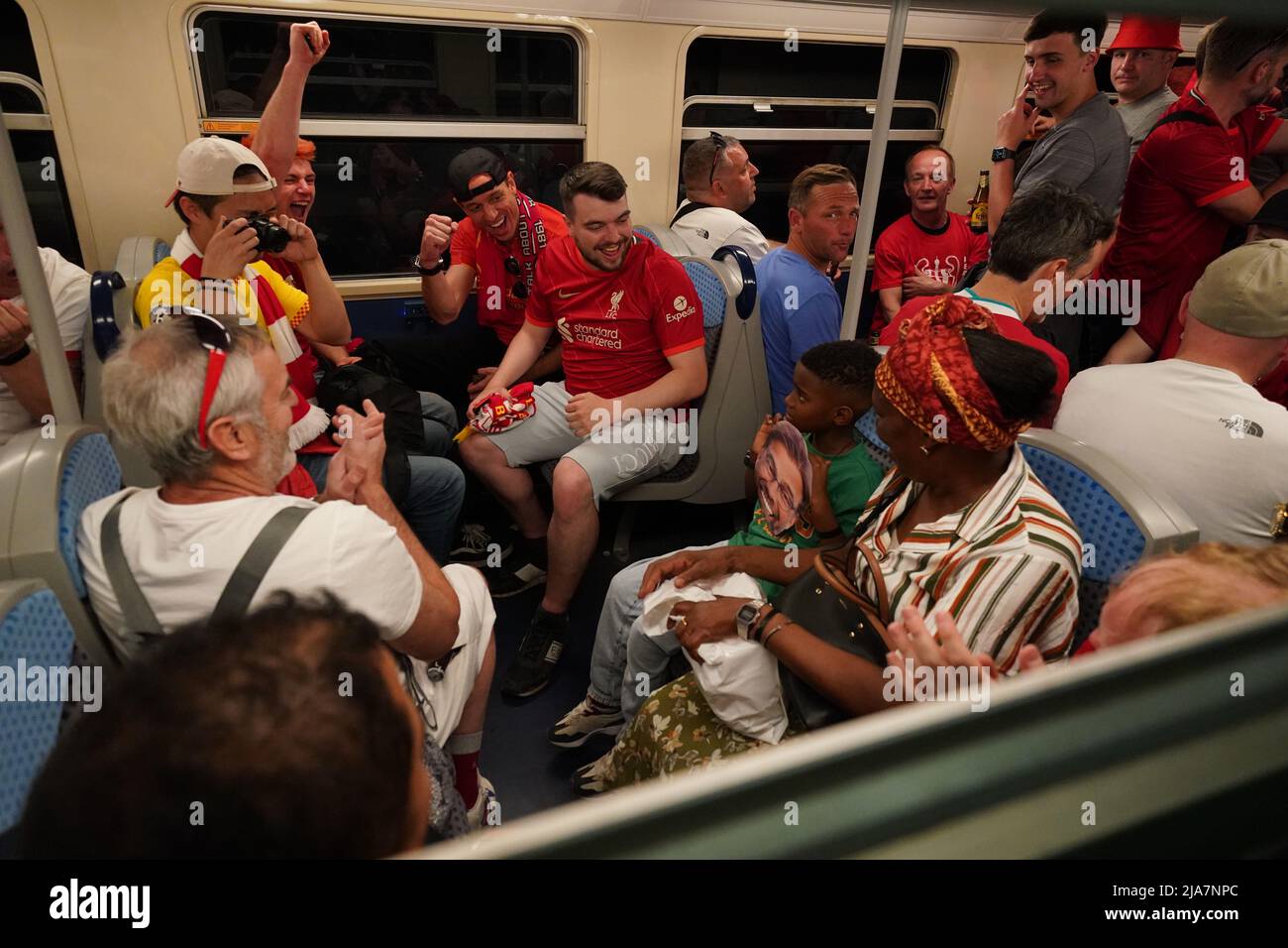 Liverpool fans give a young boy a Jurgen Klopp face mask as they board ...