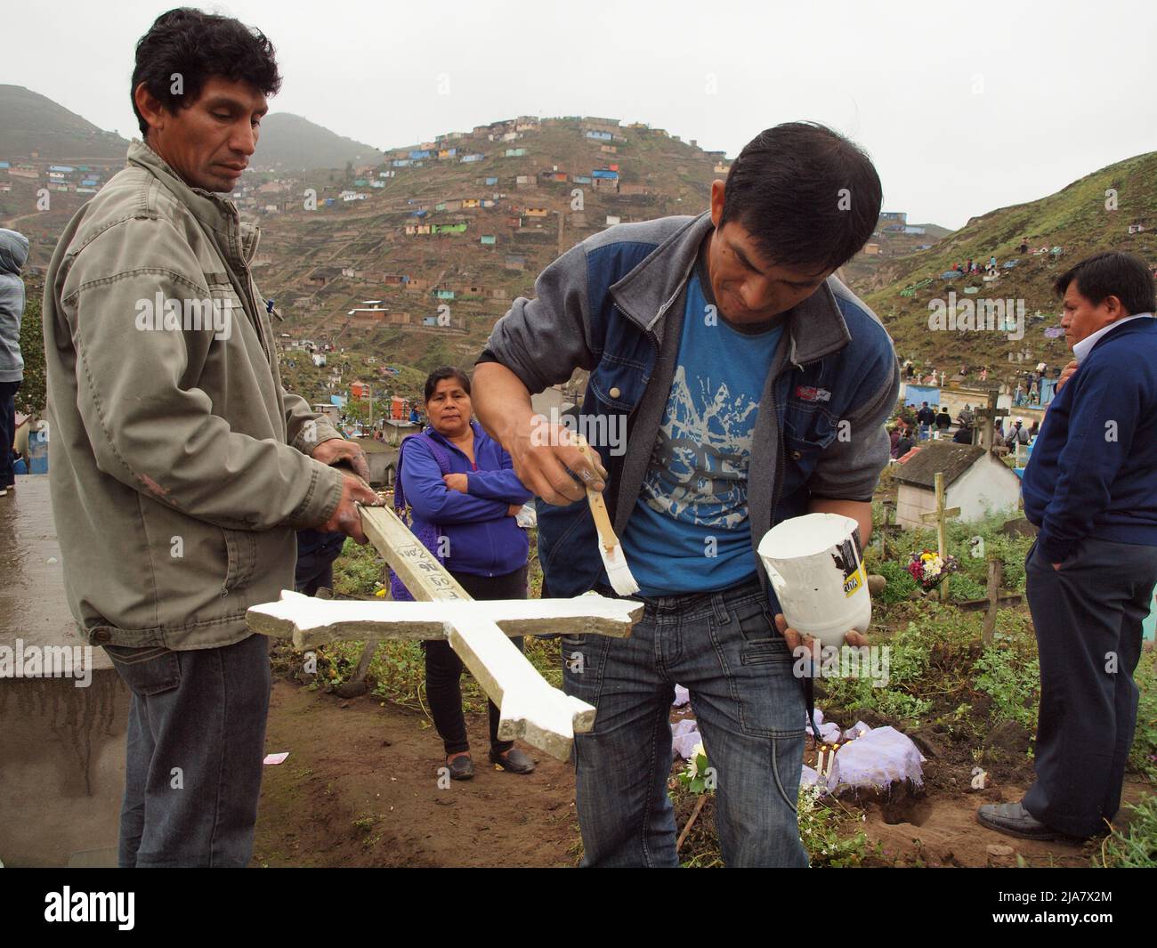 Young men painting the cross of their dead relatives in the cemetery of Nueva Esperanza, in the district of Villa el Salvador in Lima. It is one of the largest in the Americas and receives almost two million visitors each year, only on the day of the dead. Stock Photo