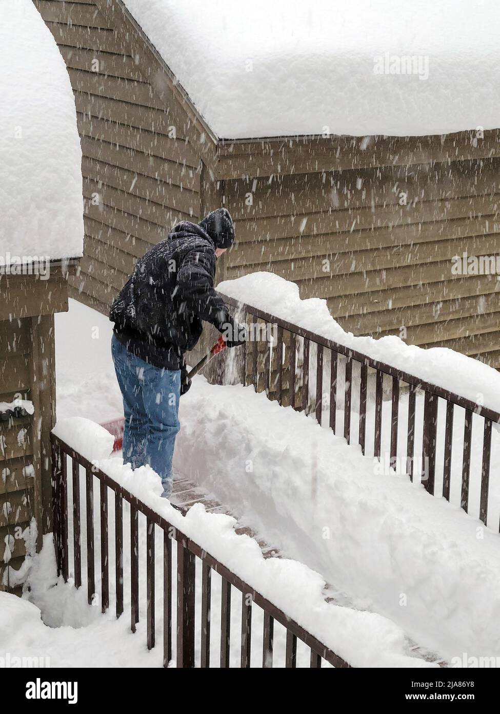 Senior man shoveling snow on a deck walkway Stock Photo