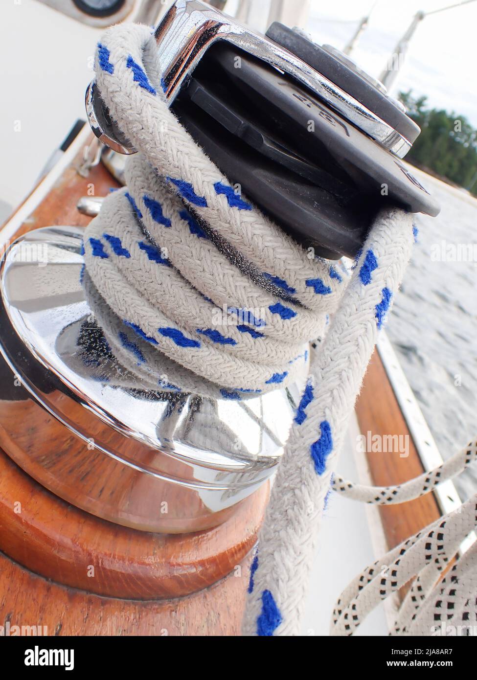 A blue and white nautical rope would around a chrome pulley on a sailboat  Stock Photo - Alamy