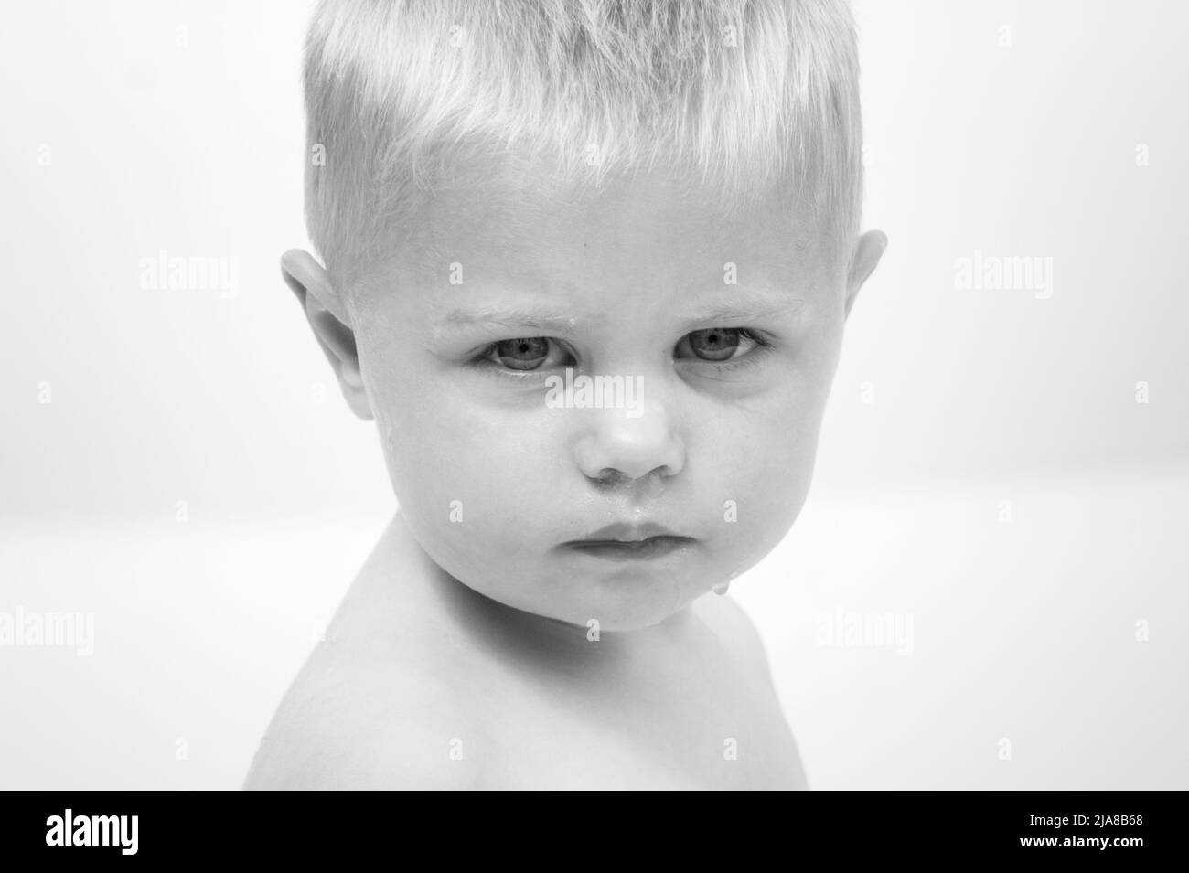 A young blonde boy stares directly at the camera with a serious look on his face Stock Photo