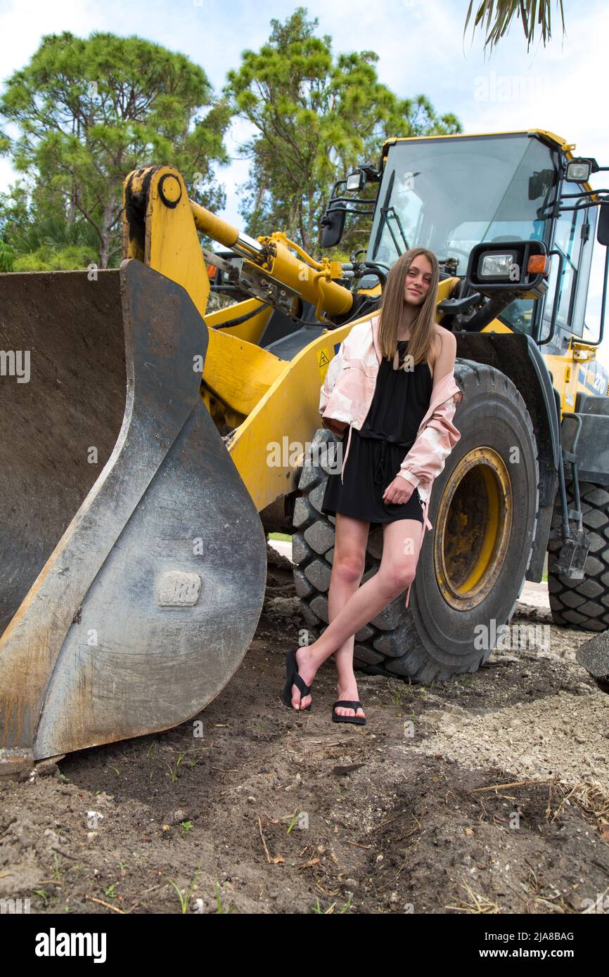 A teenage girl stands casually in front of a tractor's tire Stock Photo -  Alamy