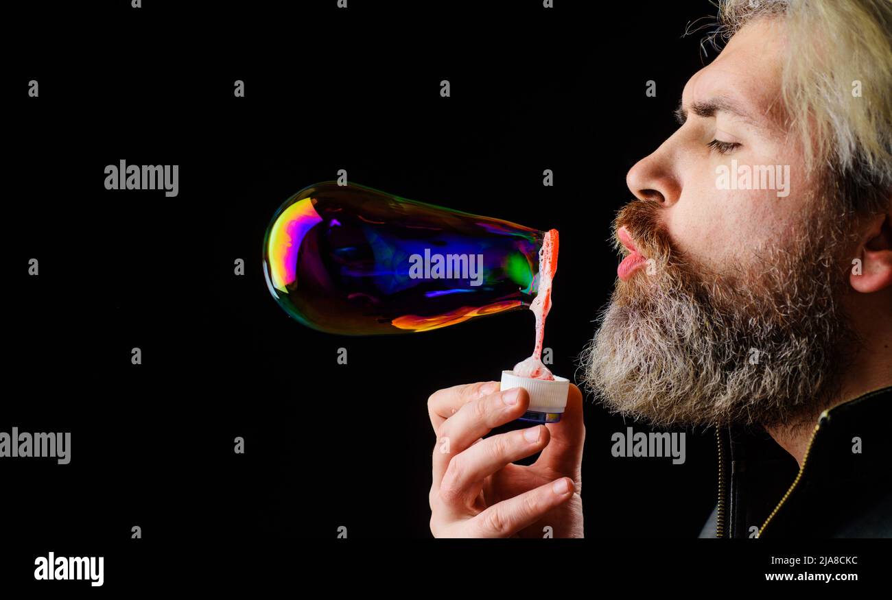 Bearded man blowing soap bubbles. Happiness. Good mood. Childhood concept. Closeup portrait. Stock Photo