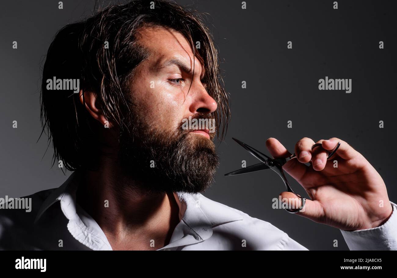Bearded man with barber scissors. Mans haircut in barber shop. Beard styling and cut. Barbershop. Stock Photo