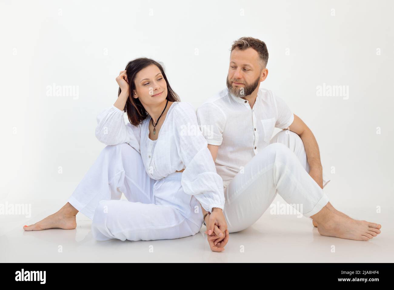 Man and woman on studio shot, couple in white outfit holding hands together. Psychology treatment for married couples Stock Photo