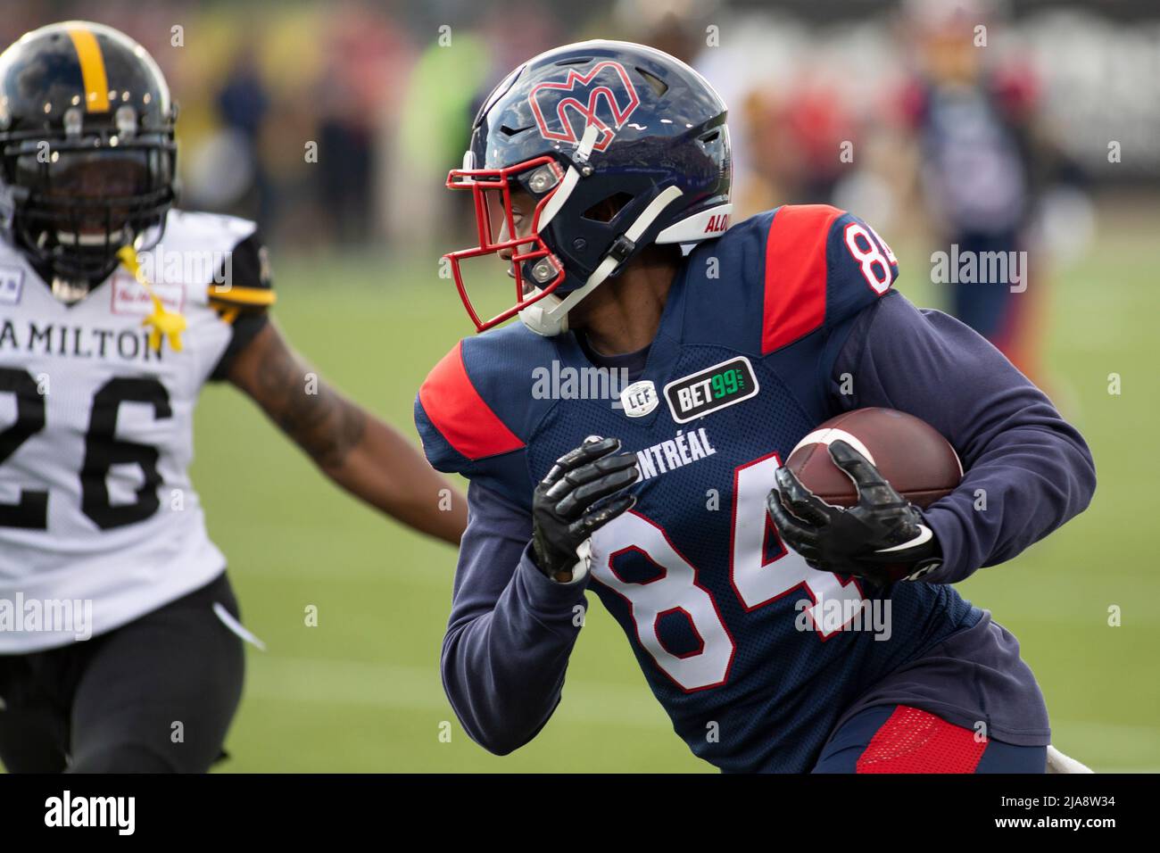 Montreal Alouettes wide receiver Reggie White Jr (84) carries the ball past  Hamilton Tiger-Cats defensive back Cariel Brooks (26) during first half  exhibition CFL football action in Hamilton on Saturday, May 28