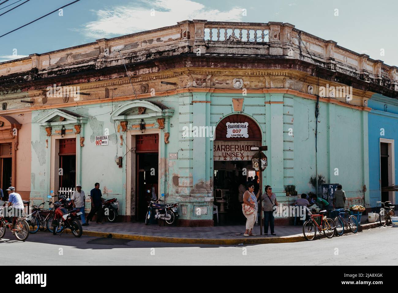 Daily life, local people in front of a corner barbershop in a Spanish colonial building in Granada, Nicaragua Stock Photo
