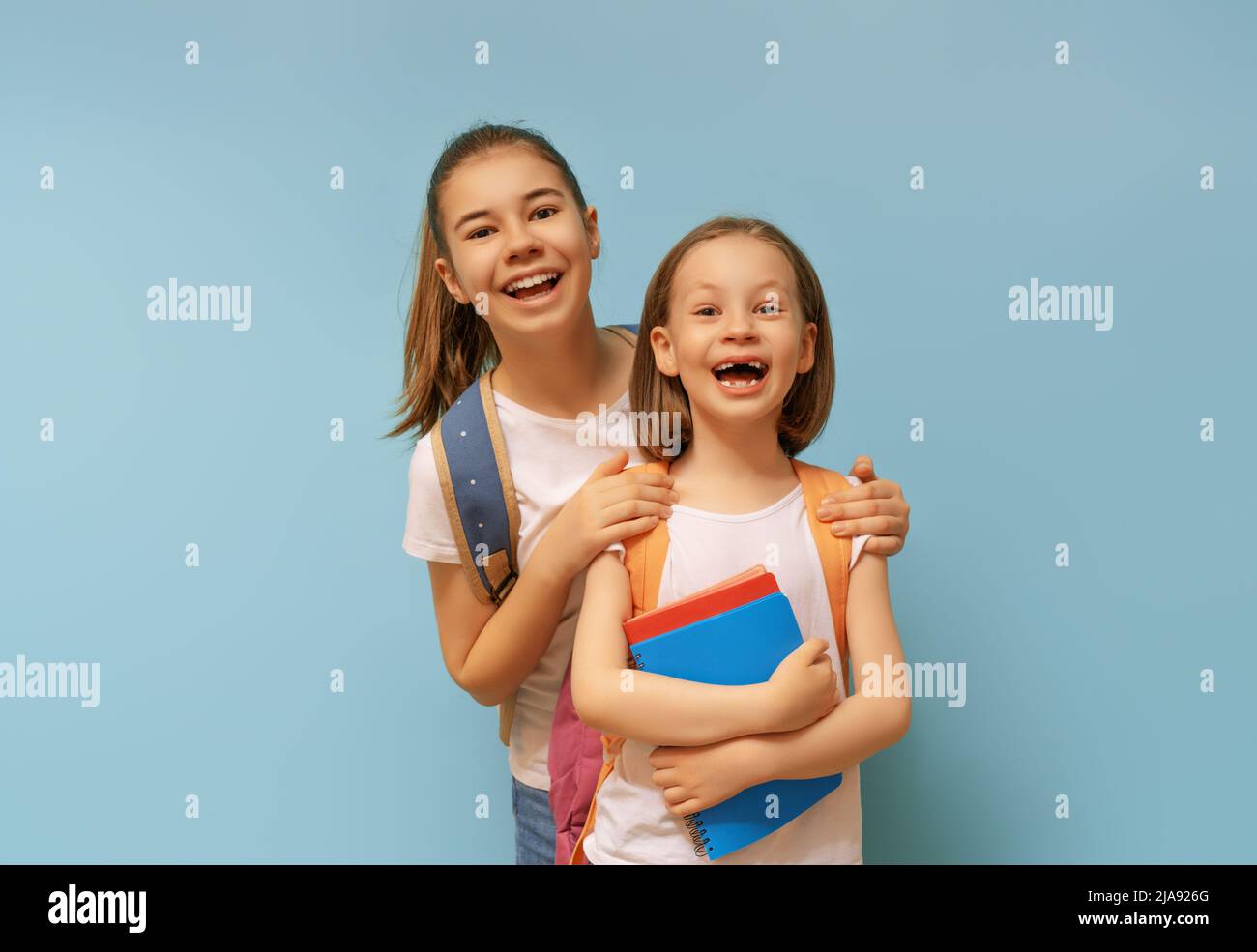 Two schoolers children standing on light blue background. Happy time