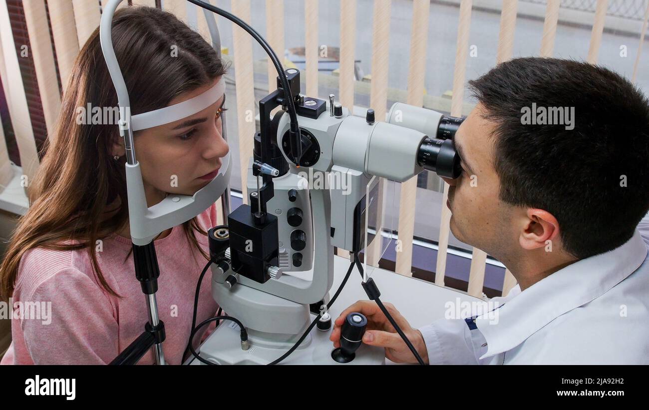 Ophthalmology treatment - a young woman checking her visual acuity with ...