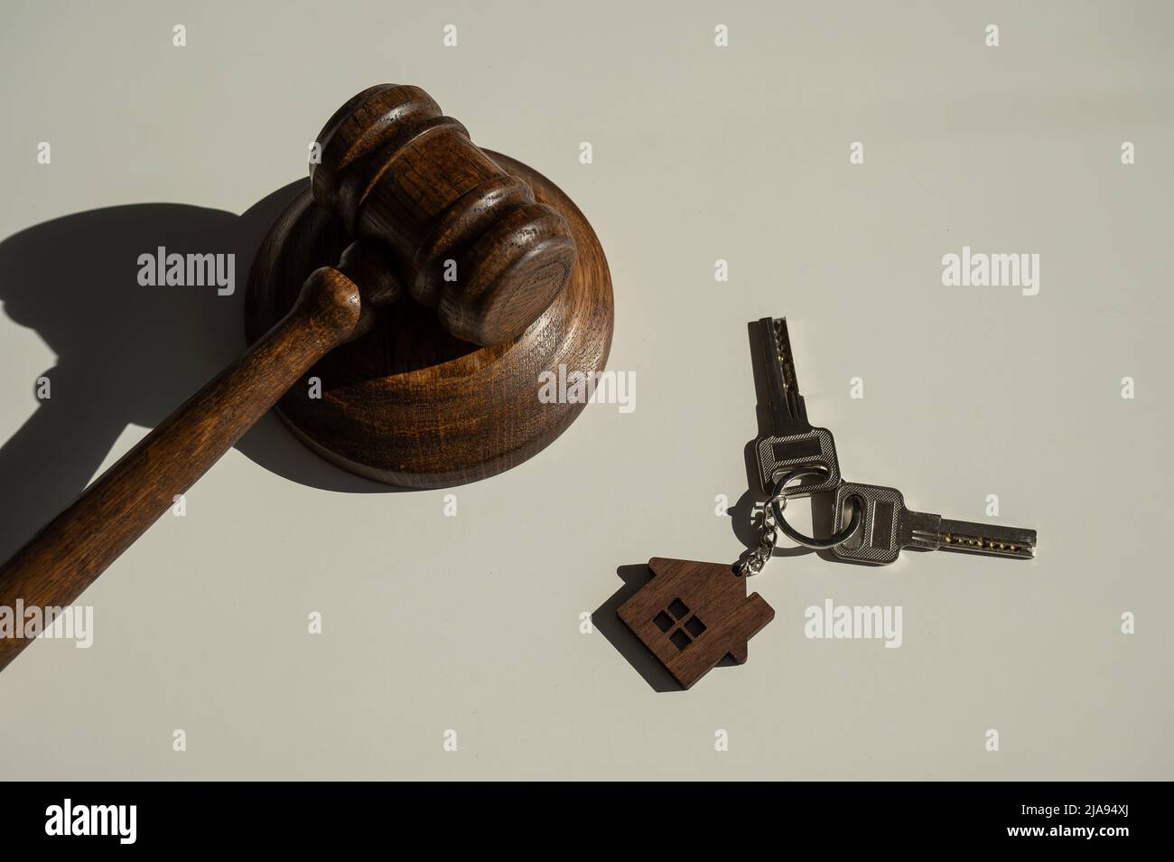 Keys with a keychain in the shape of a house and a judge's gavel on a