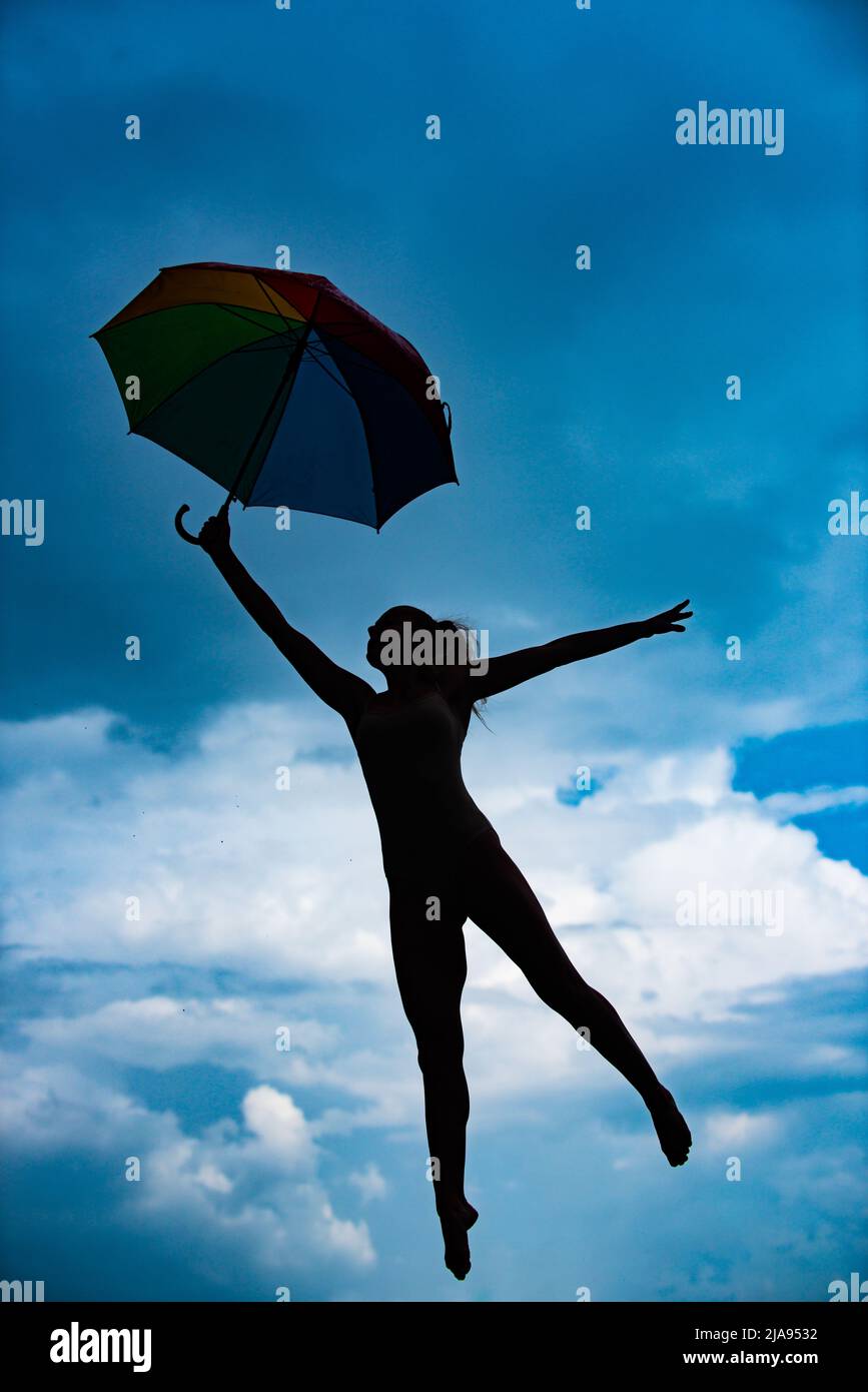 Art ballet. Silhouette of yoga woman with umbrella stretching with pose