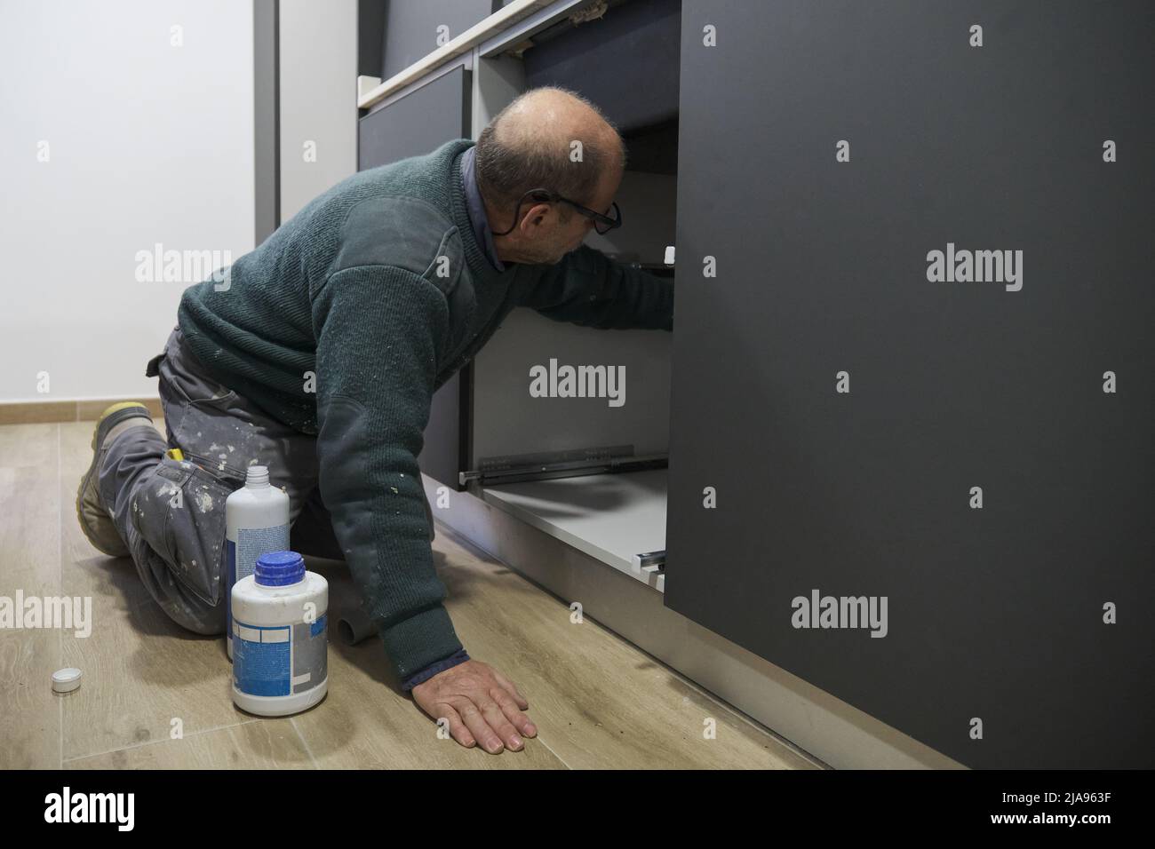 Mature plumber installing sink siphon in domestic kitchen Stock Photo