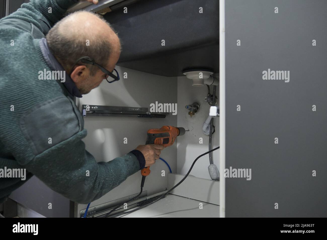 Mature technician installing water filter using a drill. Stock Photo