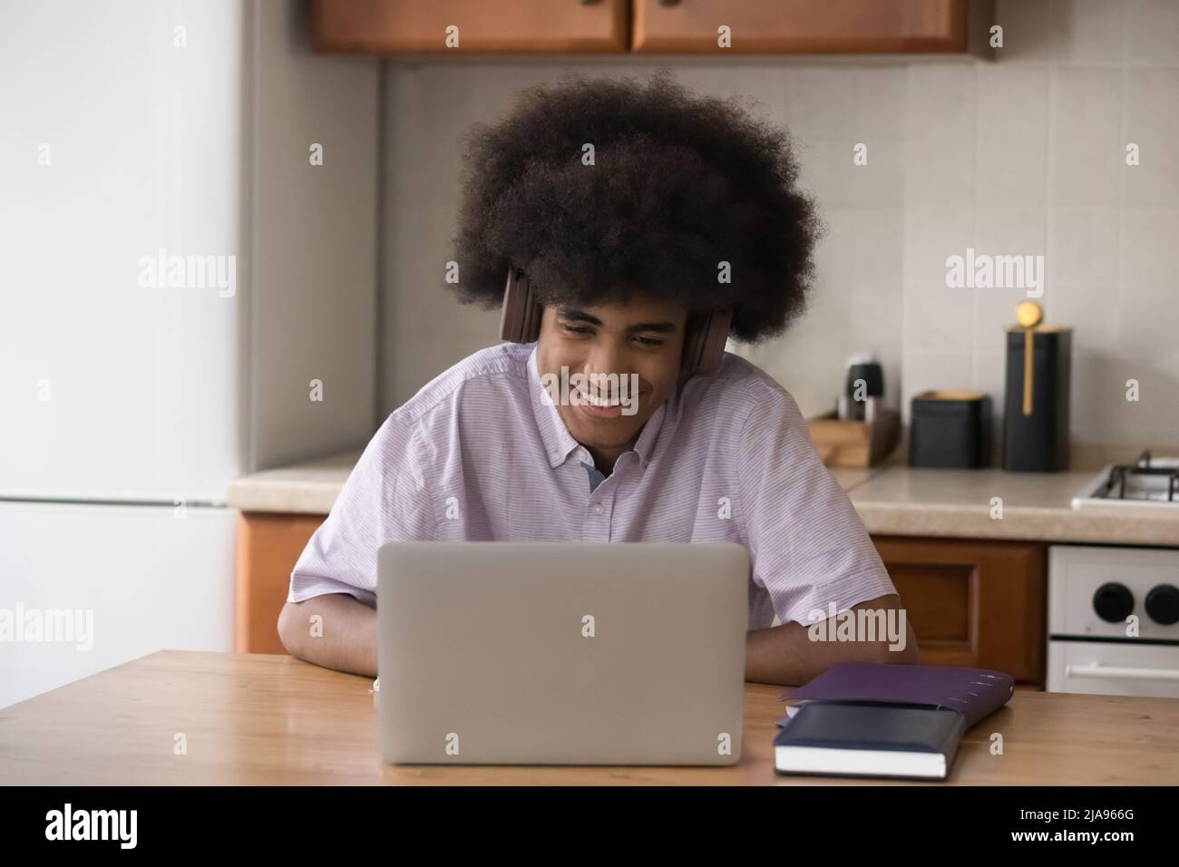 Happy student guy with retro African hairstyle using laptop Stock Photo