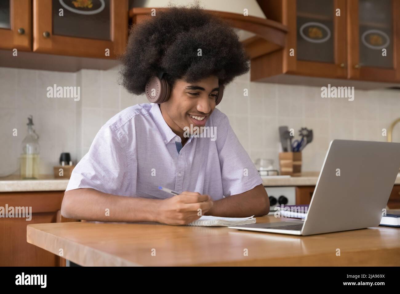 Joyful African high school student guy wearing wireless headphones Stock Photo