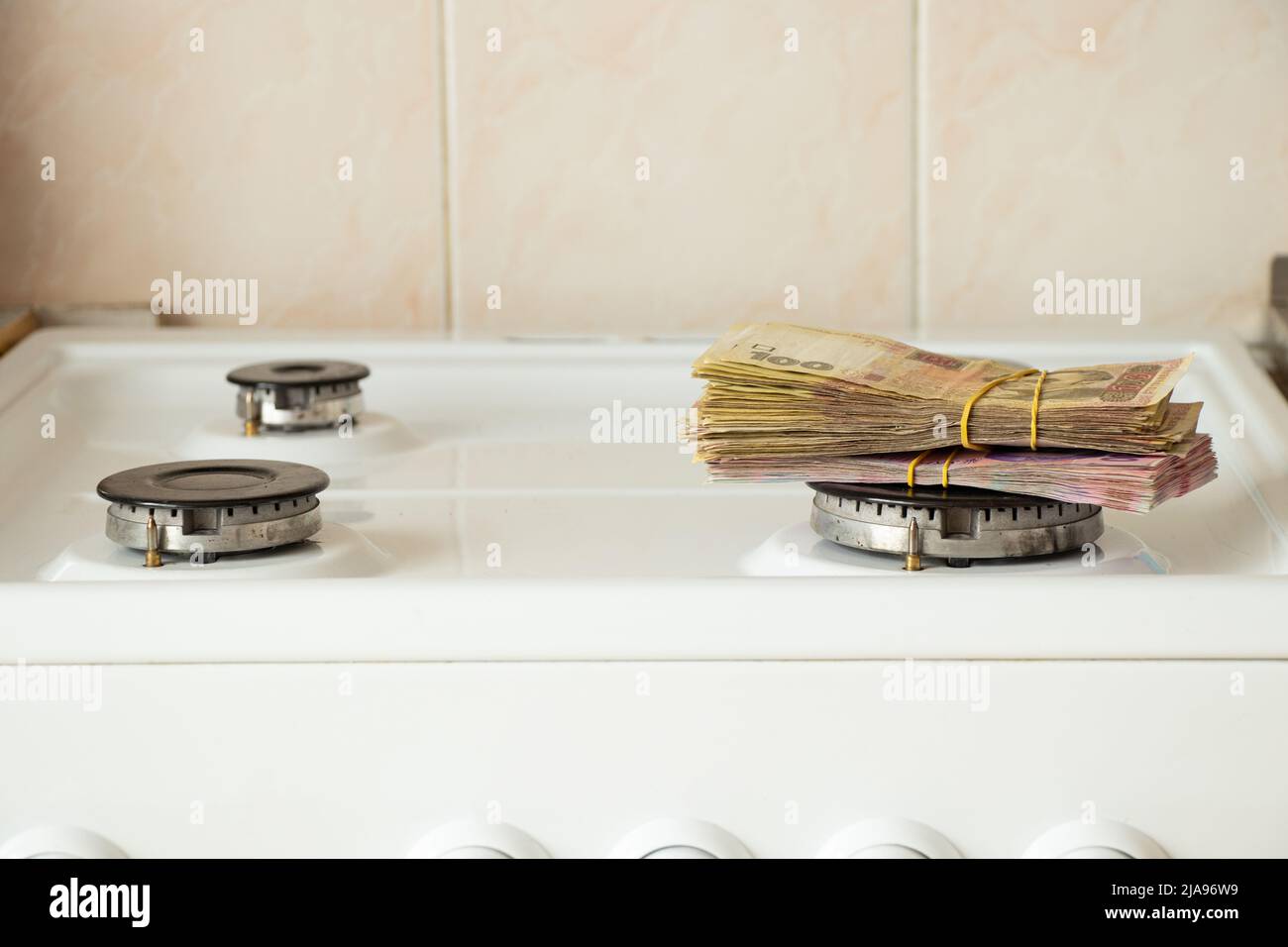 One hundred and two hundred hryvnia lie on a gas stove in the kitchen, Ukrainian hryvnia and gas, finance and economics, money and sanctions Stock Photo